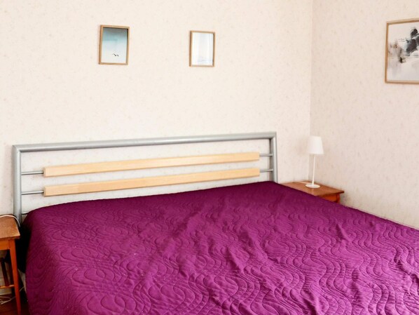 A bed with a headboard, a purple bedspread, and two framed pictures on the wall. - 9 Person Holiday Home in Bastad (Bastad)