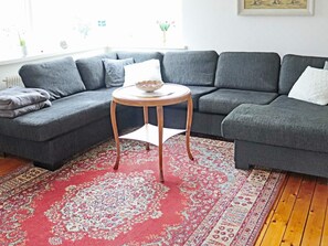 A modern living room with a grey sectional sofa, a small round wooden table, and a red patterned rug. - 9 Person Holiday Home in Bastad (Bastad)