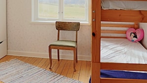 A room with a bunk bed, a chair, a window with a view of the countryside, and a patterned rug. - 9 Person Holiday Home in Bastad (Bastad)