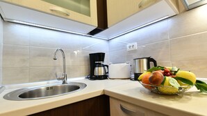 Una cocina moderna con un lavamanos de acero inoxidable, una cafetera, un tostador y un frutero sobre la encimera.