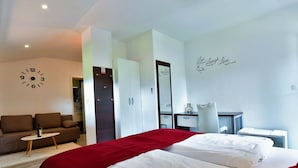 Una habitación de hotel con una cama, un sofá, un escritorio y un reloj de pared.
