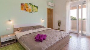A bedroom with a bed, a nightstand, a wall-mounted air conditioner, and a sliding glass door to a balcony. - Villa Lena Comfortable Holiday Residence (Marcana)