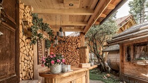 Un espacio al aire libre rústico con banco de madera, leña apilada y una estructura de madera rústica.