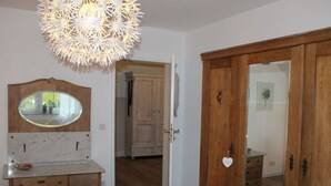 Une pièce dotée d’une armoire en bois, d’une coiffeuse en marbre avec un miroir et d’un luminaire au plafond original.