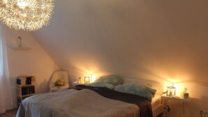 Une chambre confortable avec un grand lit, une petite table de chevet avec une lampe et un luminaire décoratif au plafond.