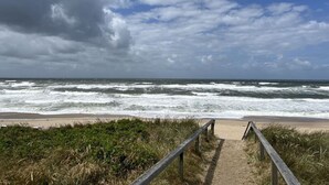 A beach path leading to the ocean with waves crashing onto the shore. - Klaar Kimming Modern Retreat (Sylt)
