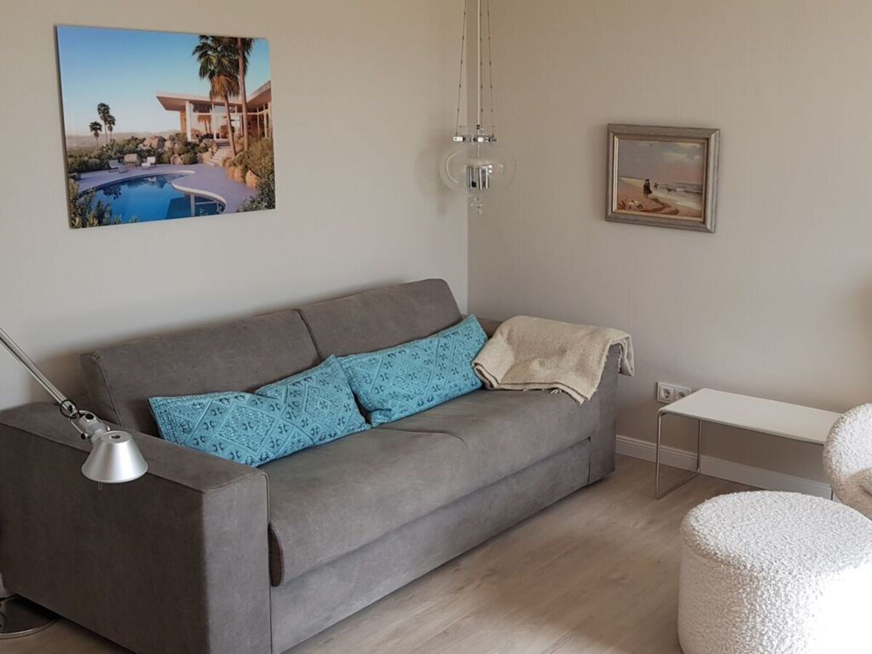 A grey sofa with patterned cushions, a small table, and a round ottoman.