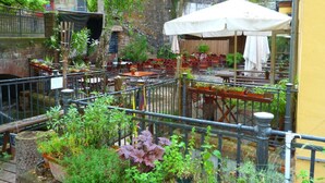 An outdoor café with tables and chairs, surrounded by potted plants and a metal fence. - Holiday Apartment Zirbelnuss (Augsburg)