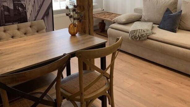 A dining area with a wooden table and chairs, a sofa with cushions, and a framed picture on the wall. - Cathedral Whispers Modern Retreat (Schwerin)