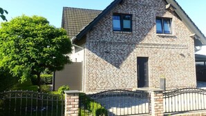 Una casa a due piani con facciata in mattoni, tetto a capanna e un piccolo portico.
