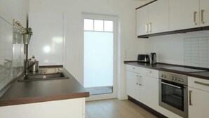 Una cucina moderna con pensili bianchi, un piano di lavoro in legno e un forno integrato.