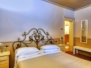 A neatly made bed with white linens, a metal headboard with intricate designs, bedside tables with lamps, and a mirror on the wall. - Apartment in Monteverdi Near Wine Tours (Monteverdi Marittimo)