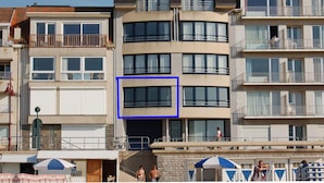 A multi-story hotel with balconies, a central arched window, and a visible entrance.