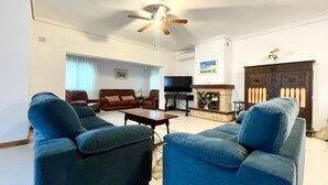Un salon équipé d’un ventilateur de plafond, d’une cheminée, d’un téléviseur et d’un ensemble de meubles comprenant un canapé.