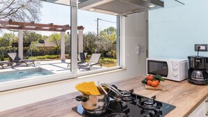 Una cocina moderna con techo de vidrio, estufa integrada, microondas y cafetera.