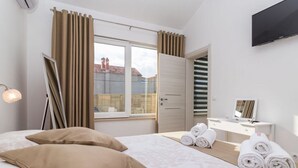 Una habitación de hotel con cama, escritorio, espejo y ventana con cortinas.