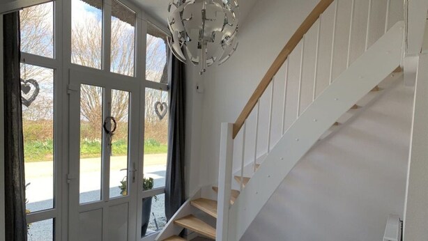 Um interior moderno com escada, uma janela grande com decorações em formato de coração e uma luminária de teto exclusiva.