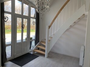 Un interior moderno con una escalera, un amplio ventanal con decoraciones con forma de corazón y una lámpara de techo original.
