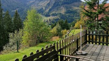 Una terraza de madera con bancos que ofrece vistas a un paisaje montañoso.