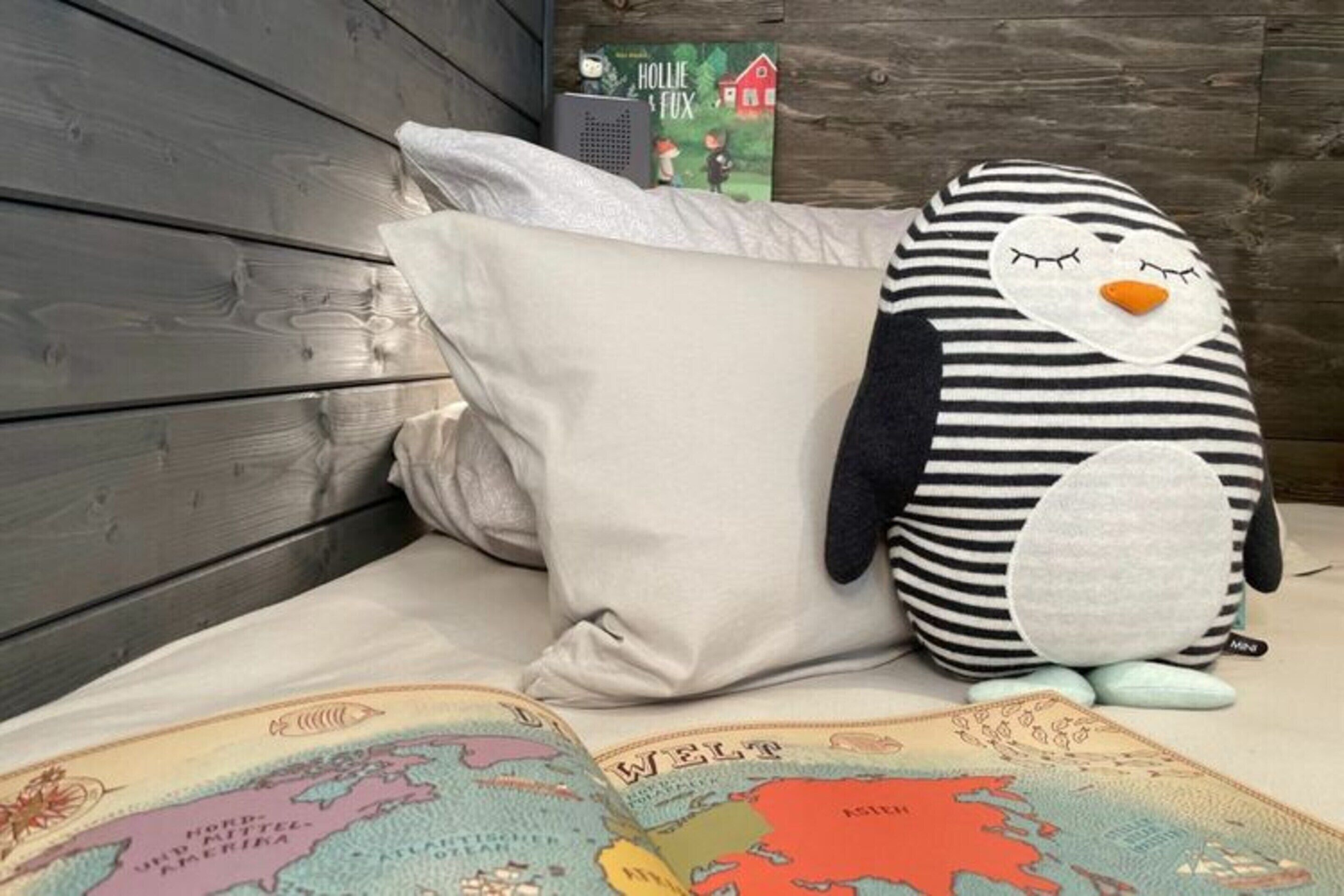 Un lit avec un oreiller et un jouet en peluche en forme de pingouin.