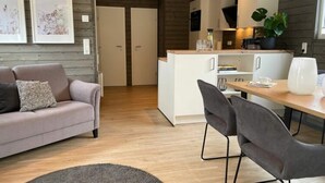 Una sala de estar moderna con un sofá, una mesa de comedor con sillas y una zona de cocina con armarios y una planta.