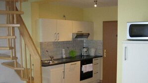 A kitchen with white cabinets, a wooden staircase, and a microwave on a white cabinet. - Muhlenhof - Muller Thurgau (Maring-Noviand)