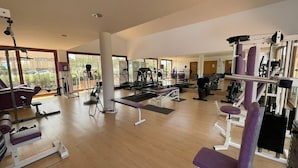 A spacious gym with various exercise equipment, large windows, and a wooden floor. - Belvilla by OYO La Tercia Resort (Murcia)