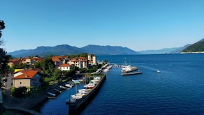 Une ville côtière dotée d’un port de plaisance, où des bateaux sont amarrés le long du quai, avec en toile de fond un paysage montagneux.