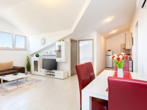 Relax in this spacious living area with a flat-screen TV, comfortable sofa, and dining table for a homey atmosphere.