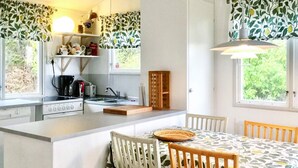 Una cocina compacta con una isla central, muebles blancos y un comedor con mesa y sillas.