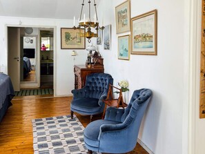 A room with a wooden floor, a blue armchair, a patterned rug, and a chandelier. - 4 Star Holiday Home in Sturko (Sturkö)