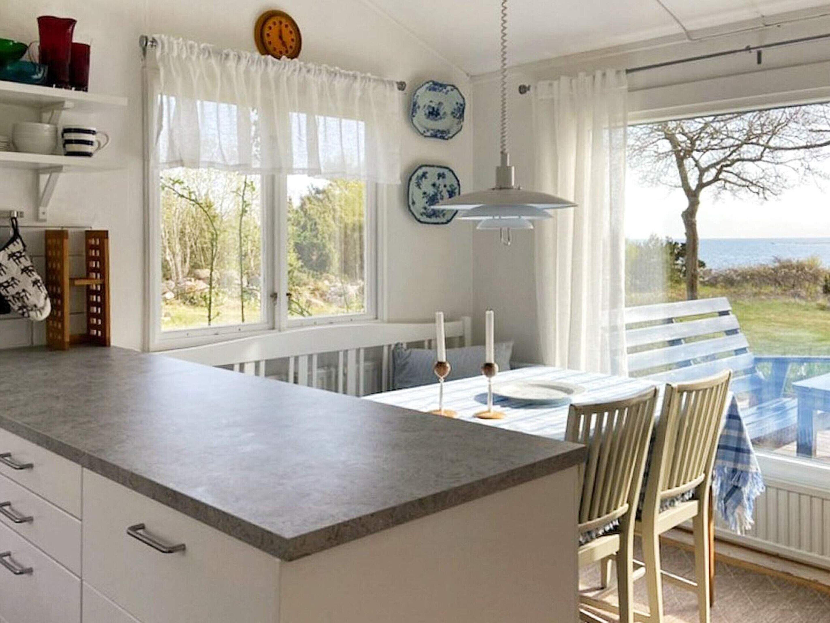 Una cocina con una isla grande, armarios blancos y vistas al exterior.