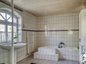 A bathroom with a sink, a bathtub, and a window. - Peter Lassau Modern Retreat (Templin)