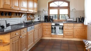 A kitchen with wooden cabinets, a built-in oven, a microwave, and a coffee maker. - Peter Lassau Modern Retreat (Templin)