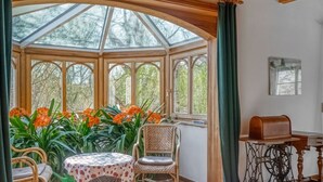 A conservatory with a table and chairs, surrounded by plants and flowers. - Peter Lassau Modern Retreat (Templin)