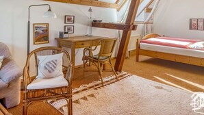 A cozy attic bedroom with a sloped ceiling, a wooden desk, a single bed, and a chair with a cushion. - Peter Lassau Modern Retreat (Templin)