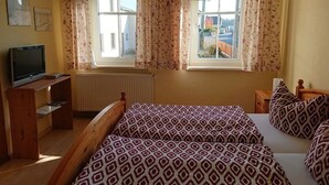 A bedroom with two beds, a TV, and a window with curtains. - Alte Kaeserei Comfortable Holiday Residence (Grimma)