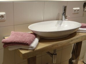 A bathroom with a white sink, a wooden countertop, and two towels. - Apartment in Lower Saxony (Faßberg)