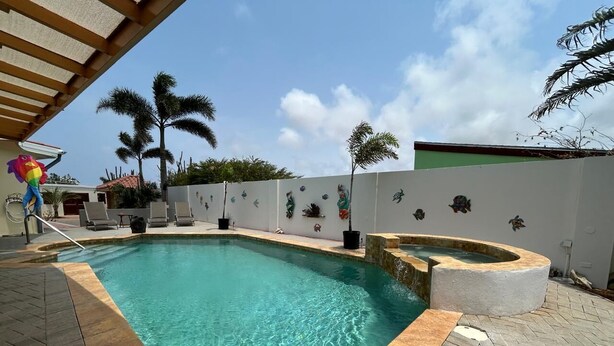 A swimming pool with a curved edge, surrounded by a tiled deck. - Paradera Palms Apt. 1 (Paradera)