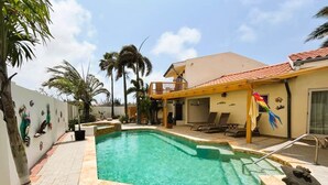A swimming pool with a tiled deck, lounge chairs, and a palm tree. - Paradera Palms Apt. 2 (Paradera)