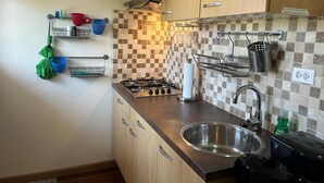 A compact kitchen with a gas stove, stainless steel sink, and a tiled backsplash. - Paradera Palms Apt. 2 (Paradera)