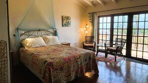 A bedroom with a bed, a ceiling fan, a window with curtains, and a chair. - Paradera Palms Apt. 2 (Paradera)