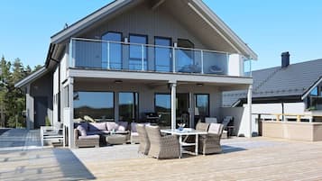 Uma casa de dois andares com varanda, móveis de exterior e um deck.