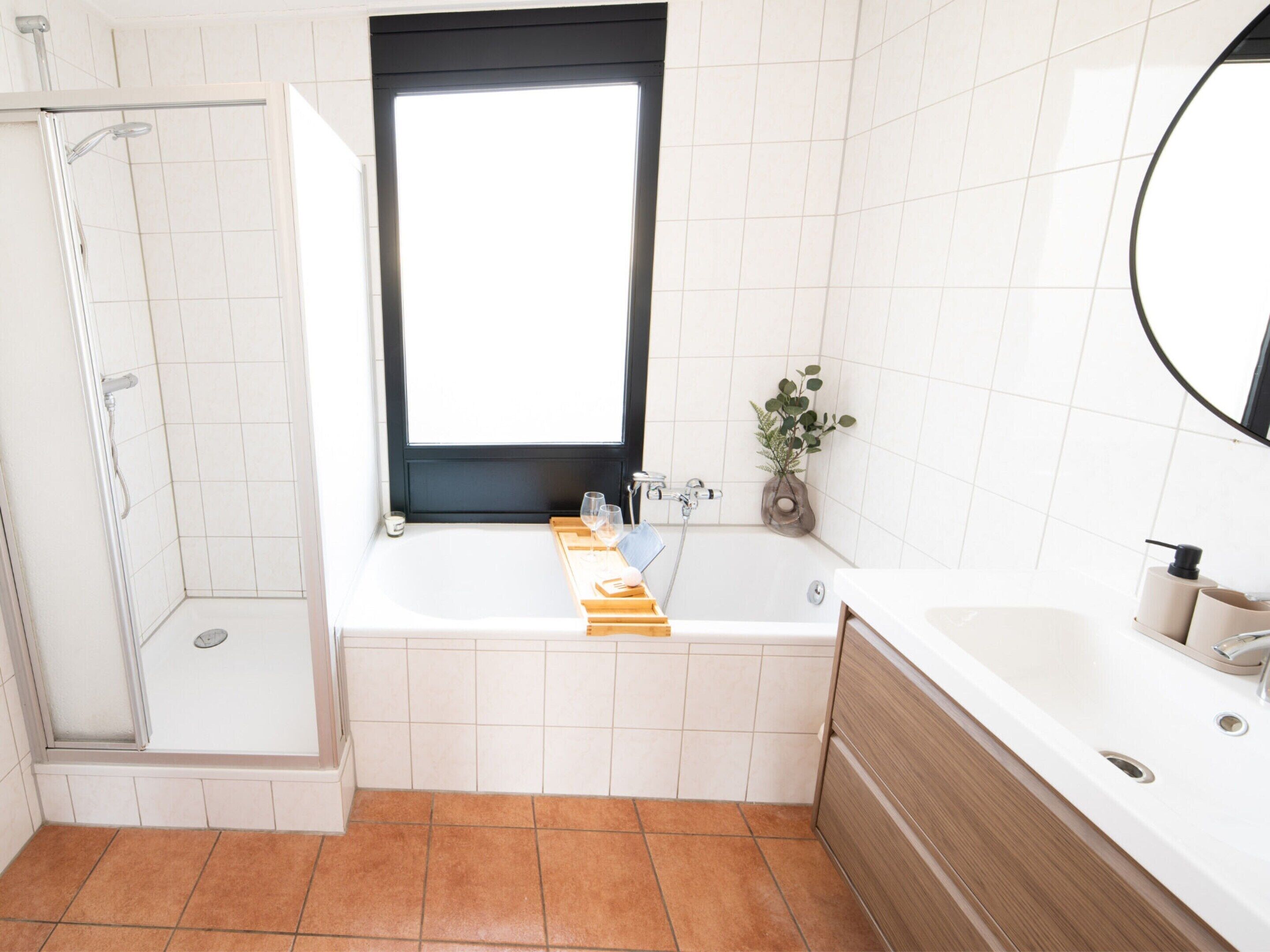 A modern bathroom with a walk-in shower, a bathtub, and a vanity with a mirror.