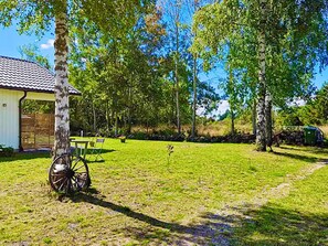 A grassy outdoor area with a wooden bench, a bicycle, and a small shed. - 4 Star Holiday Home in Kopingsvik (Kopingsvik)
