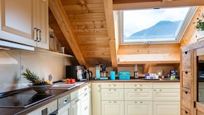 A kitchen with wooden beams, a skylight, and a view of mountains. - Holiday Apartment Zugspitzblick-riedel (Garmisch-Partenkirchen)