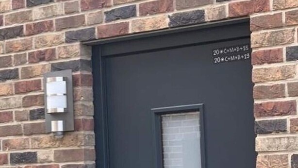 Une porte noire avec une fenêtre verticale et une fente pour le courrier sur le côté gauche.