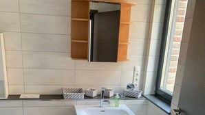 Une petite salle de bain avec un lavabo blanc, des toilettes et un miroir au-dessus du lavabo.