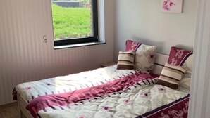 Une chambre à coucher avec un lit, une fenêtre et un tableau accroché au mur.