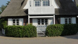 A traditional thatched-roof building with a white facade, a balcony, and a gated entrance. - Kaiserhof \"lake View\" (Kellenhusen)